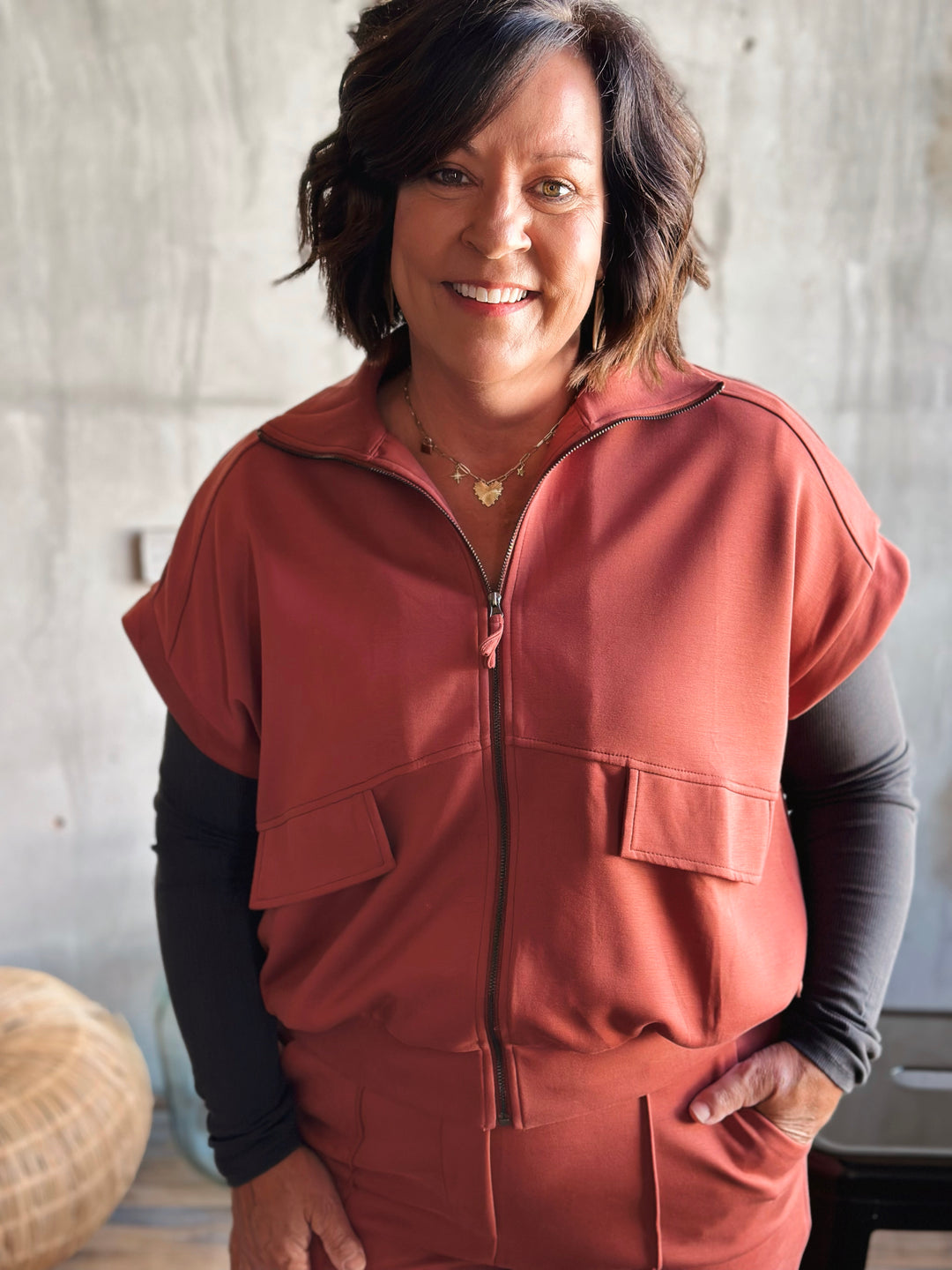 Person wearing a pink sleeveless jacket with a neutral background
