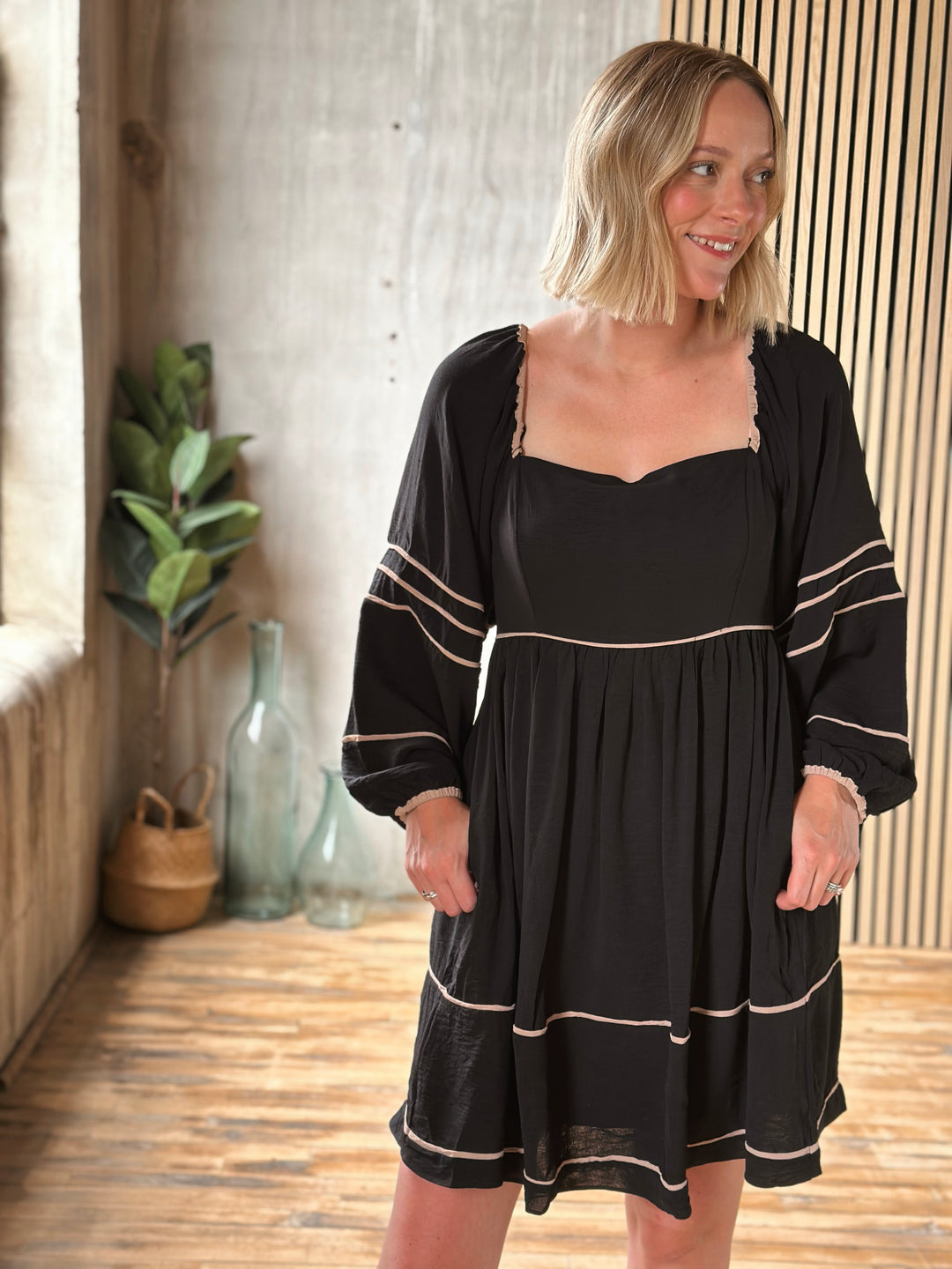 Woman wearing a black dress with white trim indoors