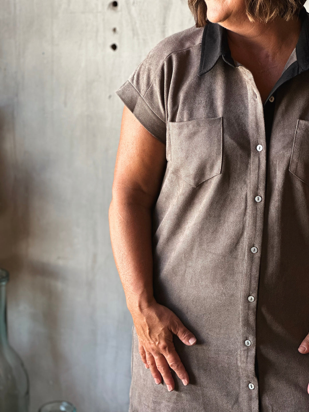 Person wearing a gray apron against a wooden background