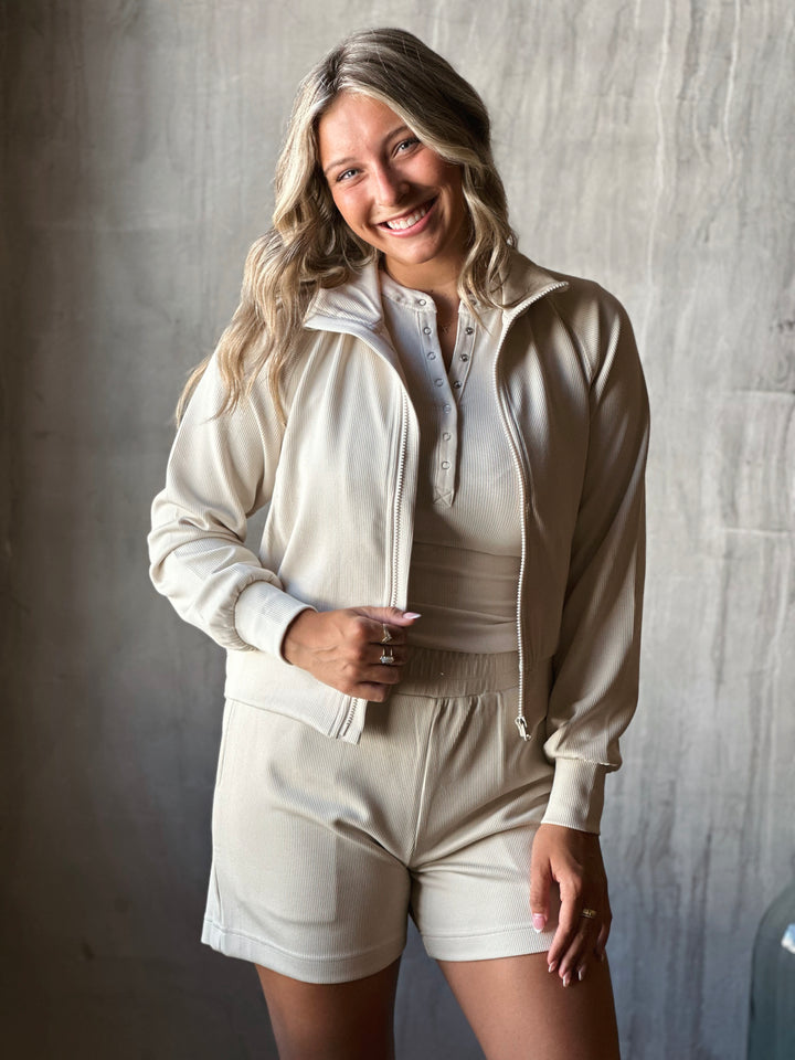 Woman wearing a beige tracksuit against a gray background