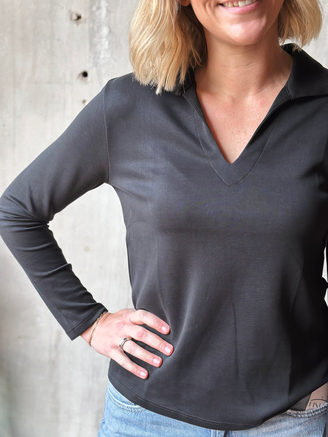 Person wearing a dark gray long-sleeve shirt against a neutral background