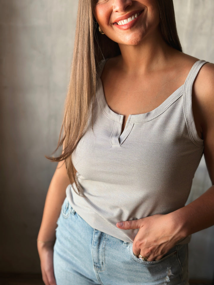 Woman wearing a striped tank top and jeans against a neutral background