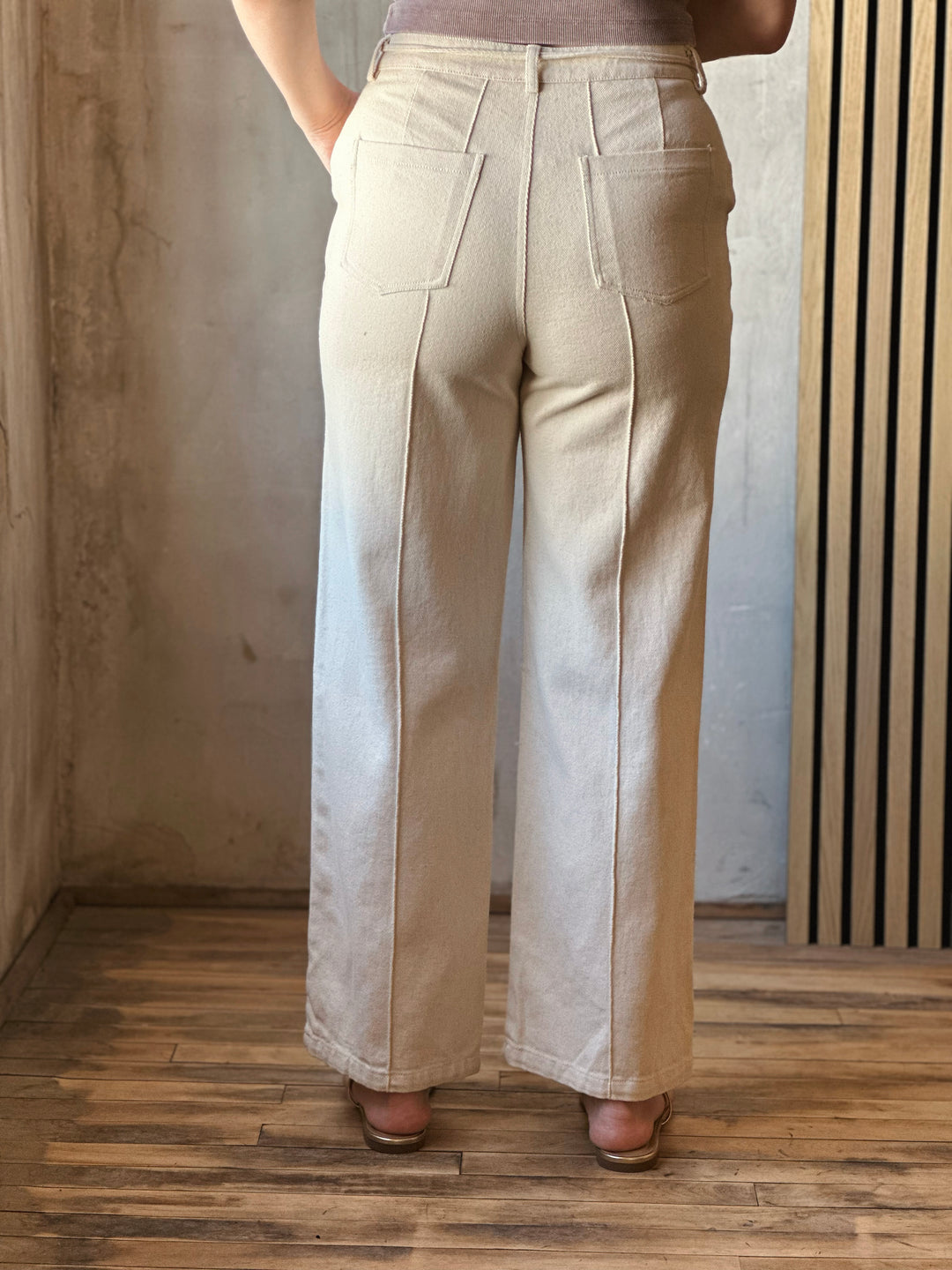 Back view of model wearing Tie Waist Pants in a oatmeal hue with back pintuck seams.
