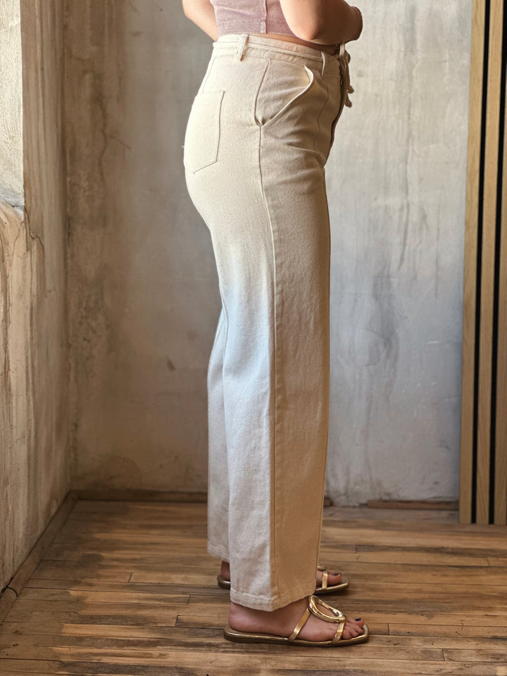 Side view of model wearing Tie Waist Pants in a oatmeal hue with side seams.