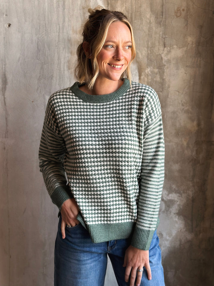 Woman wearing a patterned sweater against a textured wall