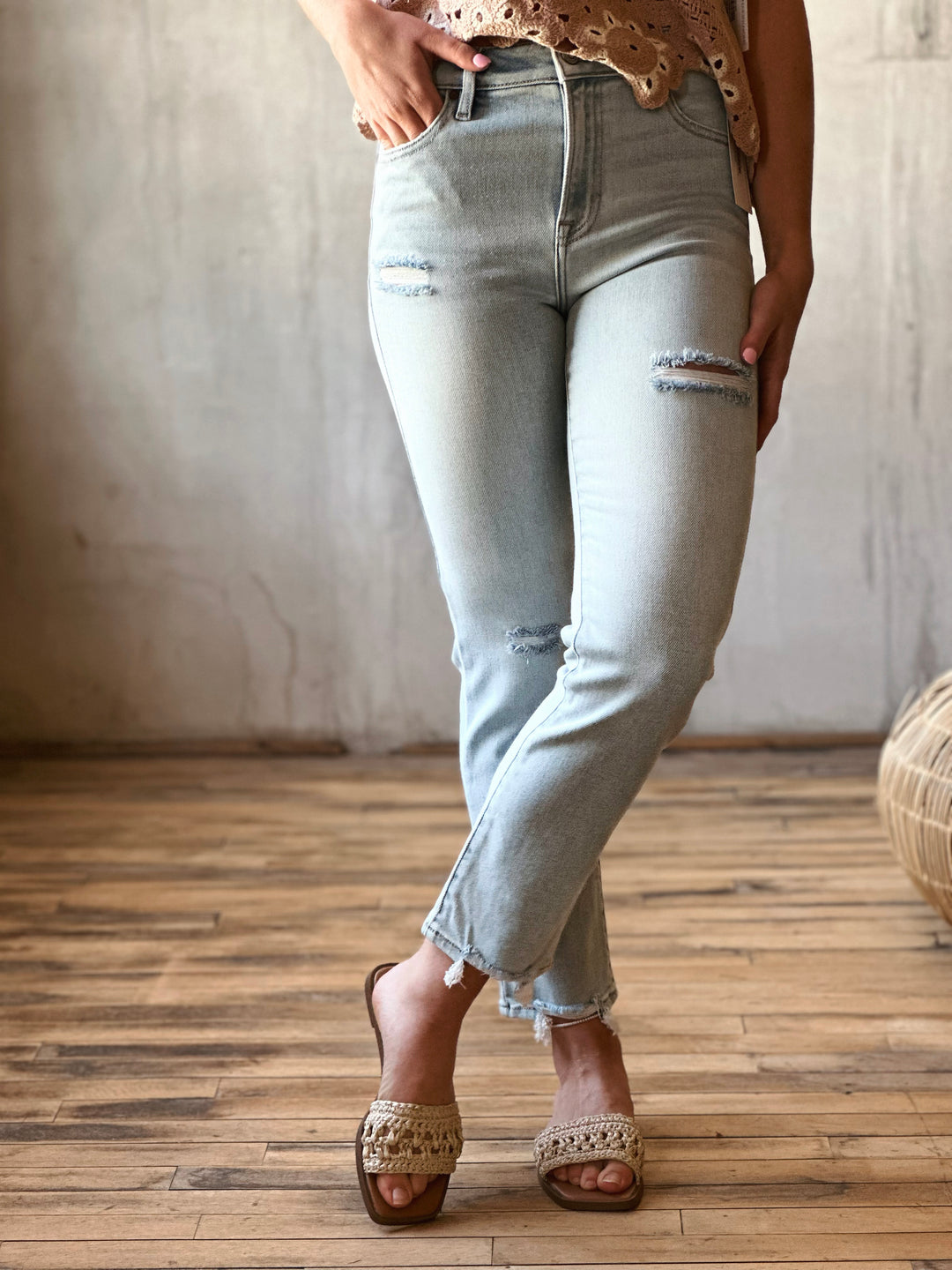 Front view of model wearing high-rise cigarette skinny jeans in a classic light blue wash with distressing