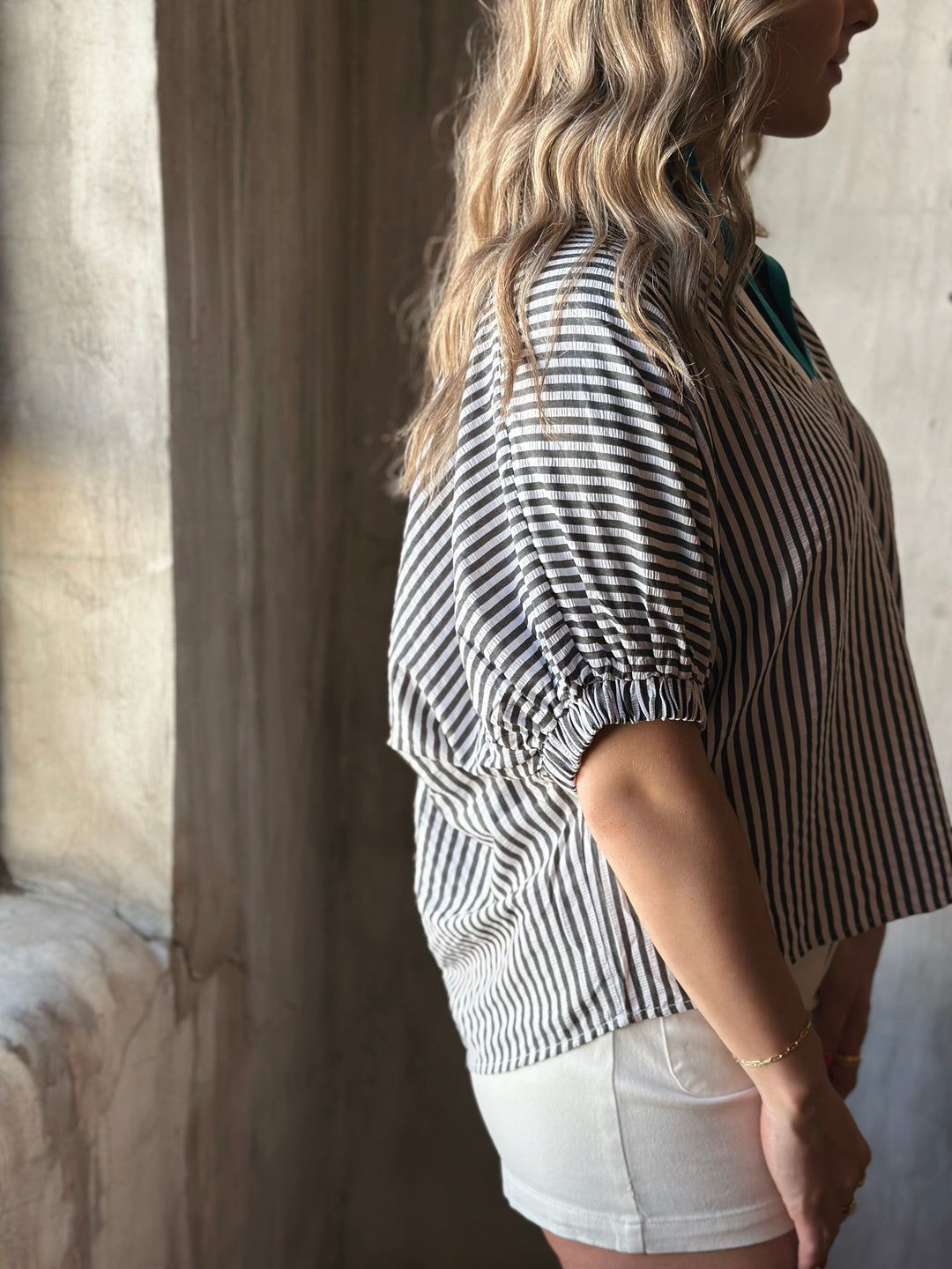 Side view of model wearing a striped high neck dolman top. The multicolor rib band split neck adds a touch of playful contrast.