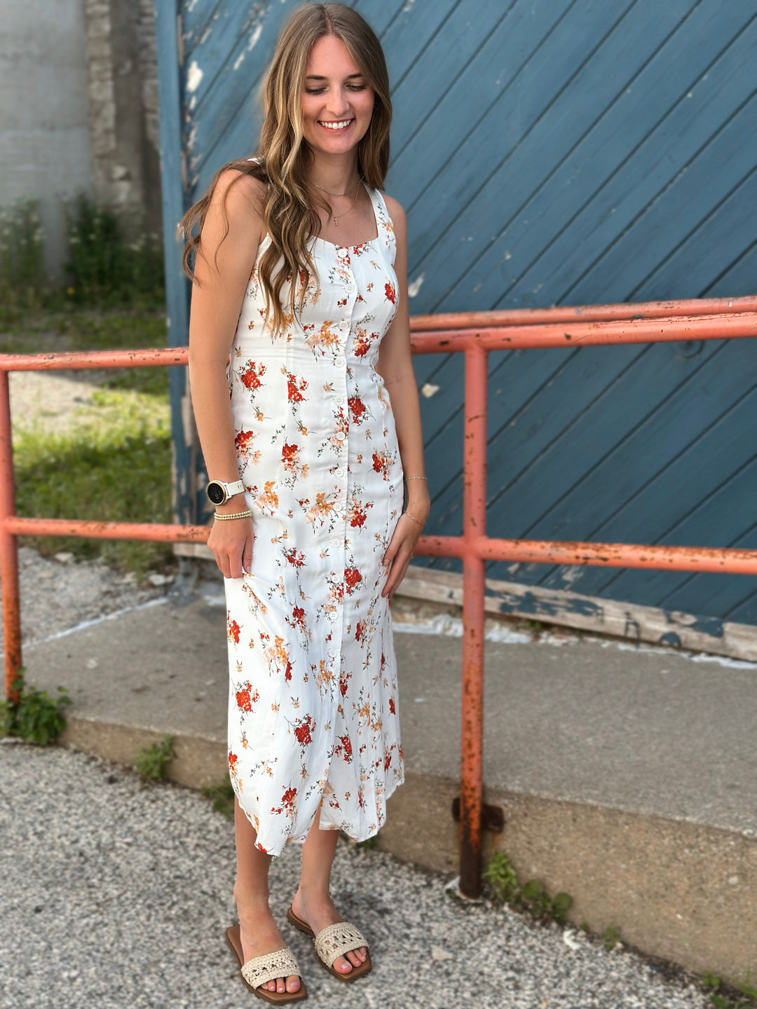 Front view of model wearing midi dress with floral print in ivory with multicolored flowers, it also has a button down front and a sleeveless design
