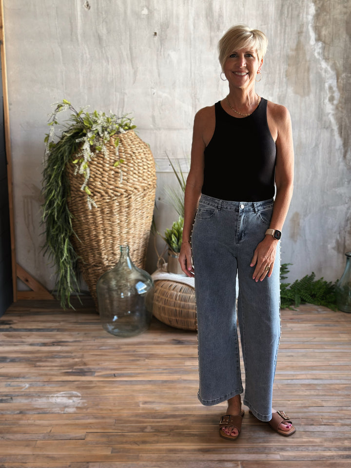 Full body front view with jeans of Black fitted bodysuit round neckline and tank straps