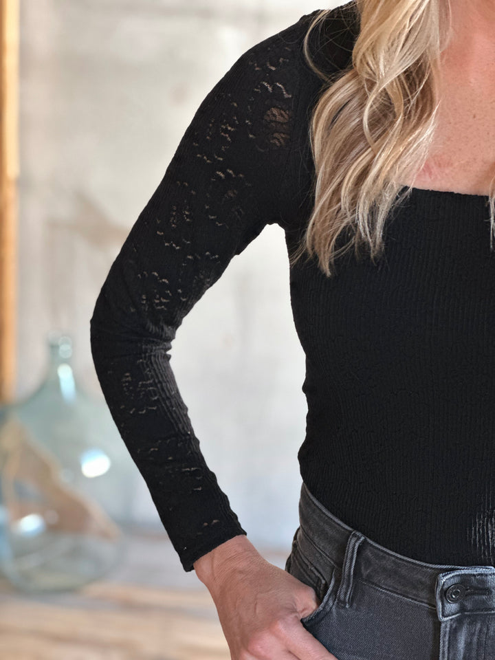 Person wearing a black long-sleeve top with a blurred background