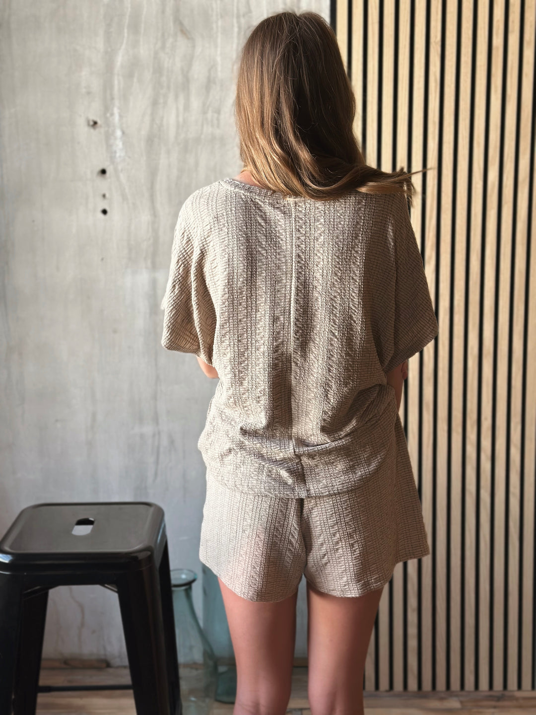 Back view of model wearing textured knit top & shorts set with elastic waist in the color taupe