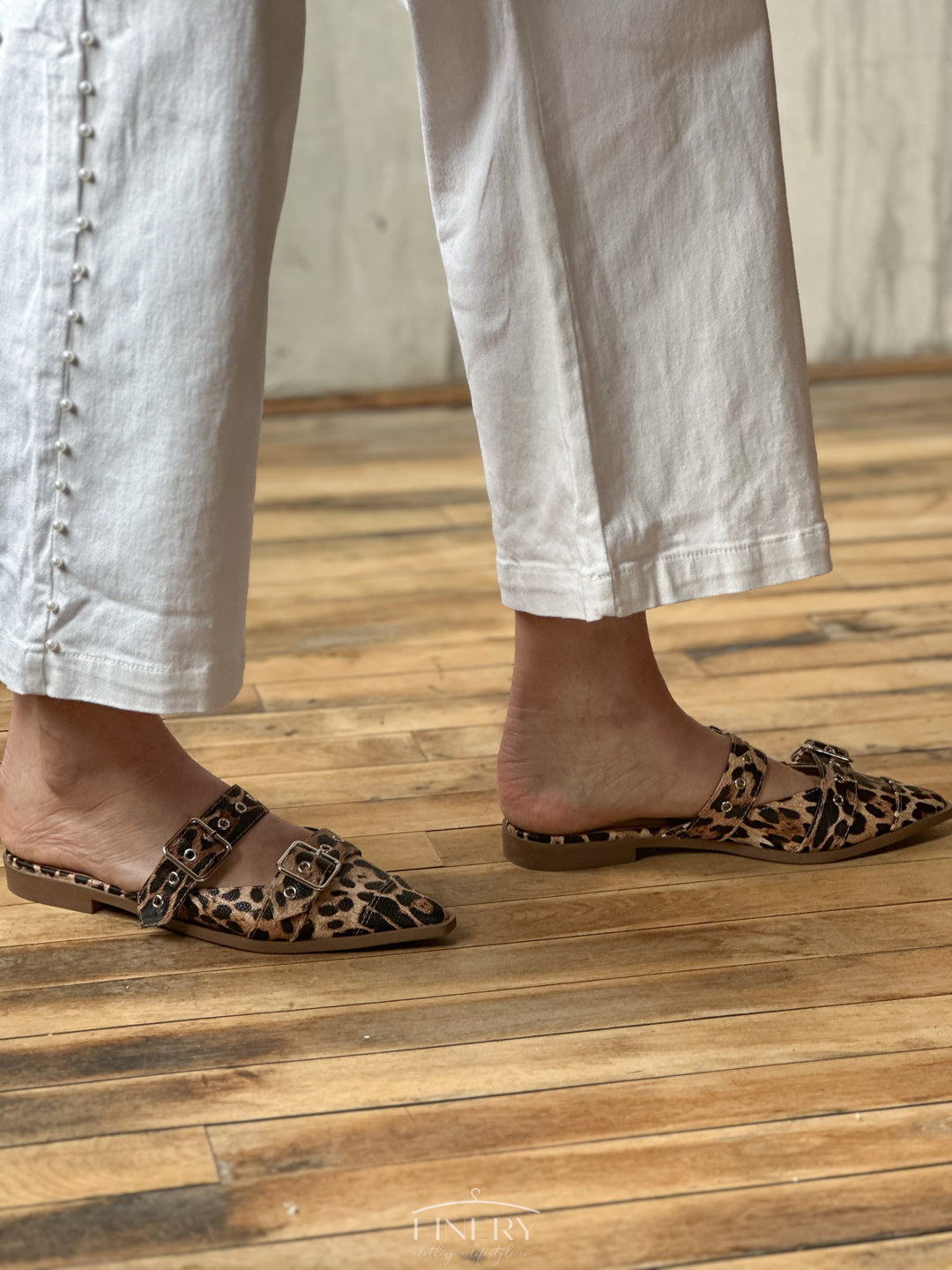 Side view of flat sandals that are closed toe with a cheetah print design, and two straps that have buckles on them