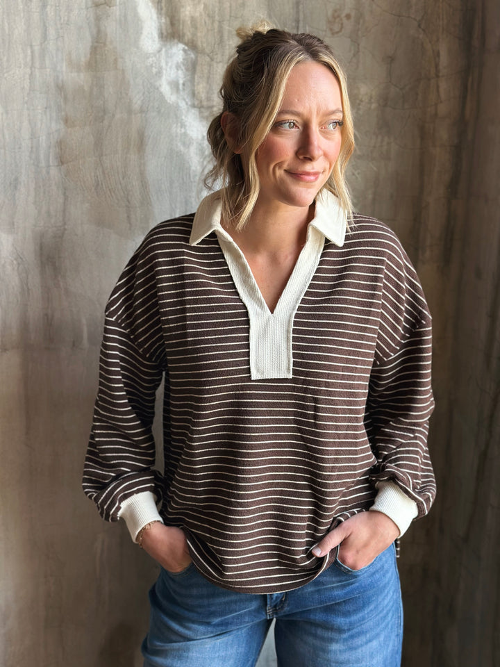 Woman wearing a striped shirt with a white collar against a textured wall.