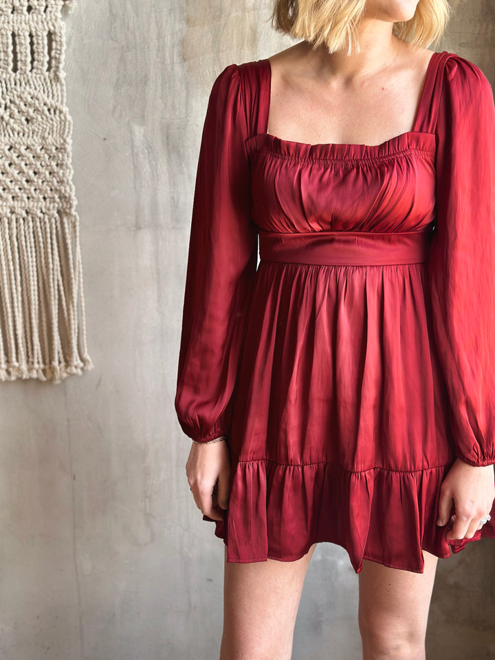 Red dress worn by a person against a neutral wall.