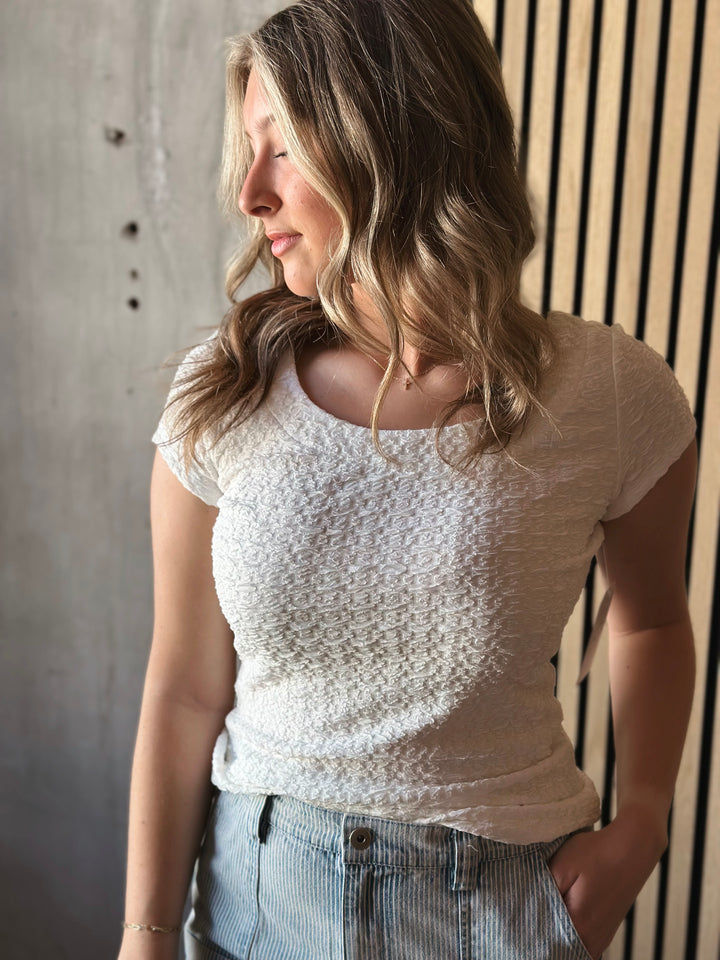 Front view of model wearing Popcorn Textured Knit Double Scoop Neckline Cap Sleeve Top in the color white