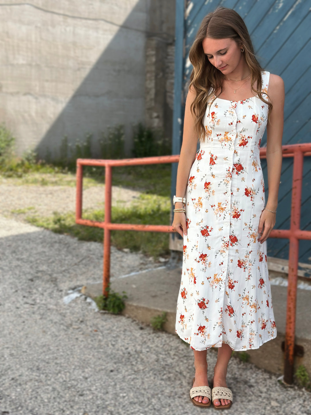 Front view of model wearing midi dress with floral print in ivory with multicolored flowers, it also has a button down front and a sleeveless design