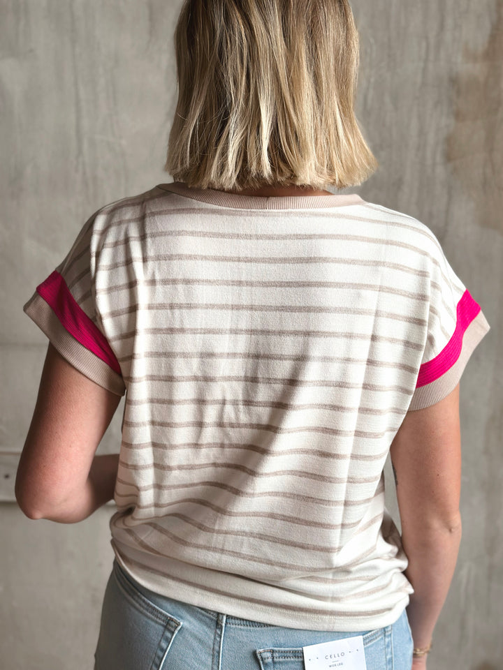 Person wearing a striped shirt with pink accents against a plain background