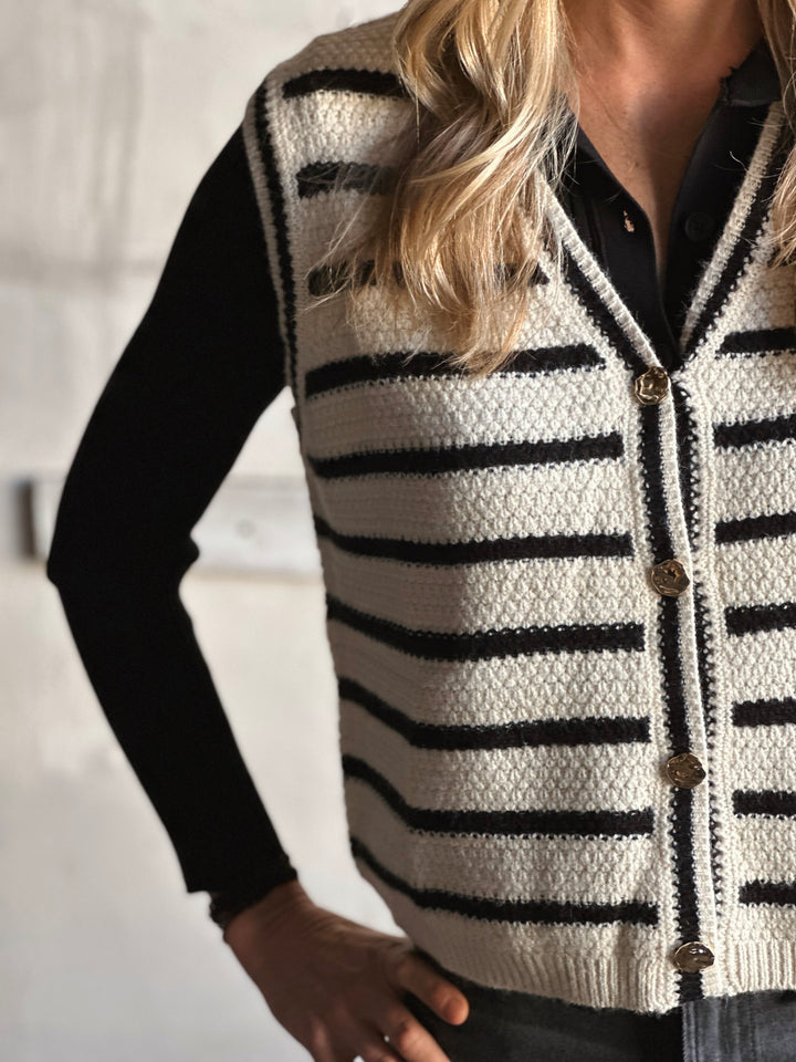 Person wearing a black and white striped cardigan with a blurred background