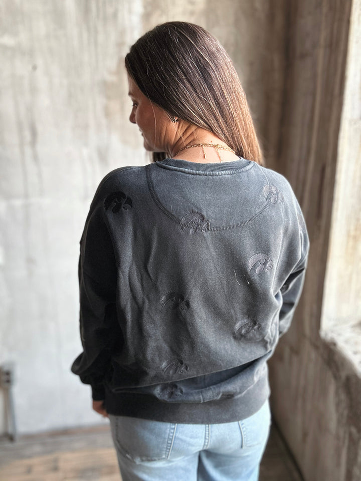 Person wearing a dark gray distressed sweatshirt in a room with neutral walls.