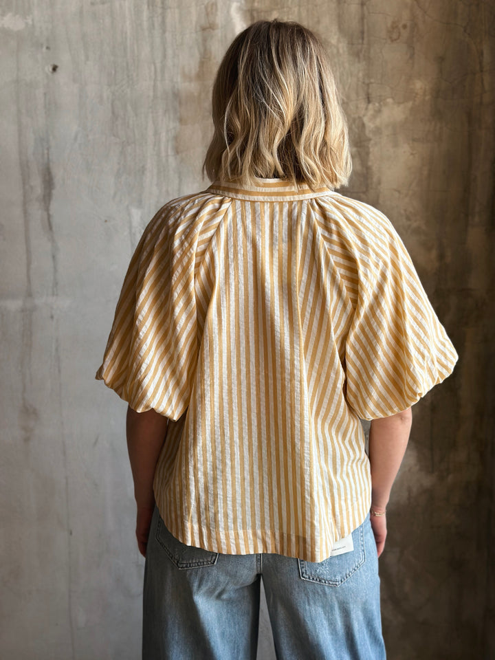 Person wearing a yellow striped shirt against a textured wall
