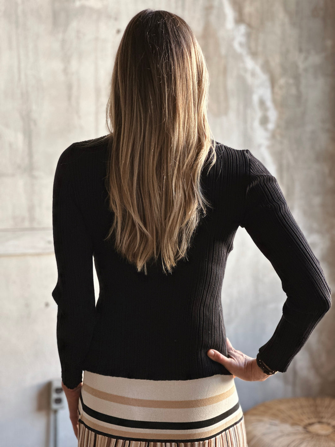 Person wearing a black sweater with a neutral background