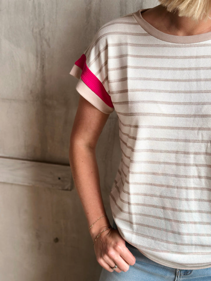 Person wearing a striped shirt with a pink sleeve against a neutral background