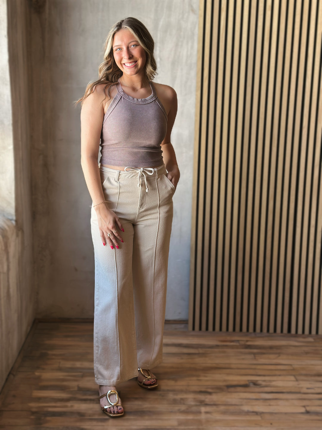 Front view of model wearing Tie Waist Pants in a oatmeal hue with front pintuck seams and tie waist