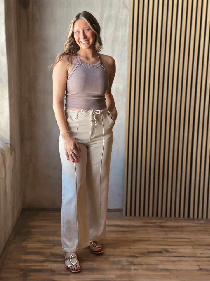 Front view of model wearing Tie Waist Pants in a oatmeal hue with front pintuck seams and tie waist