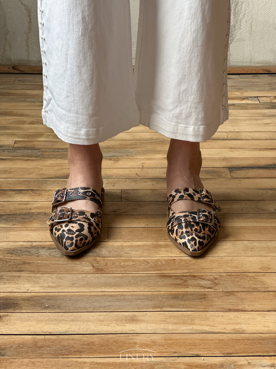 Front view of flat sandals that are closed toe with a cheetah print design, and two straps that have buckles on them