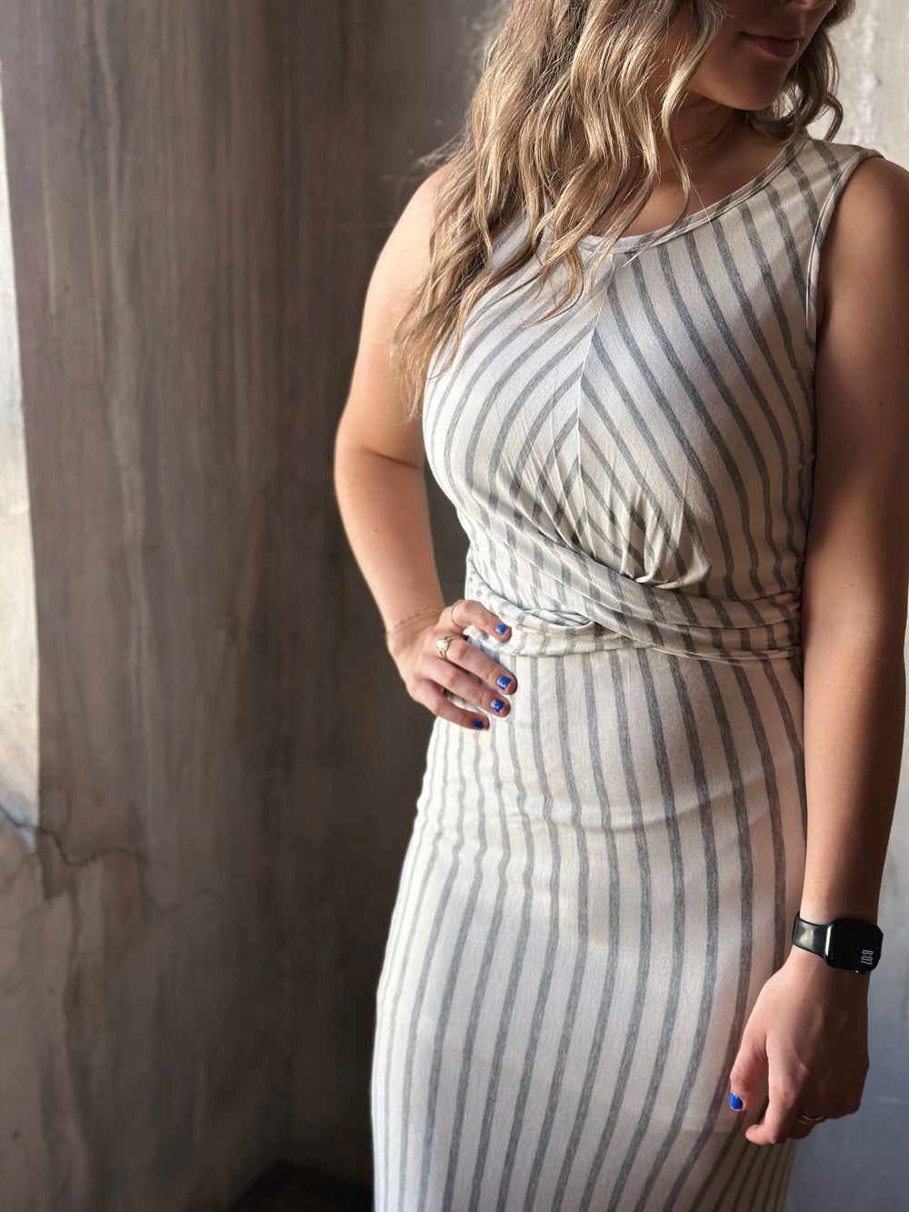 Front view of model wearing a front twist sleeveless dress with white and heather gray stripes and a rounded neckline
