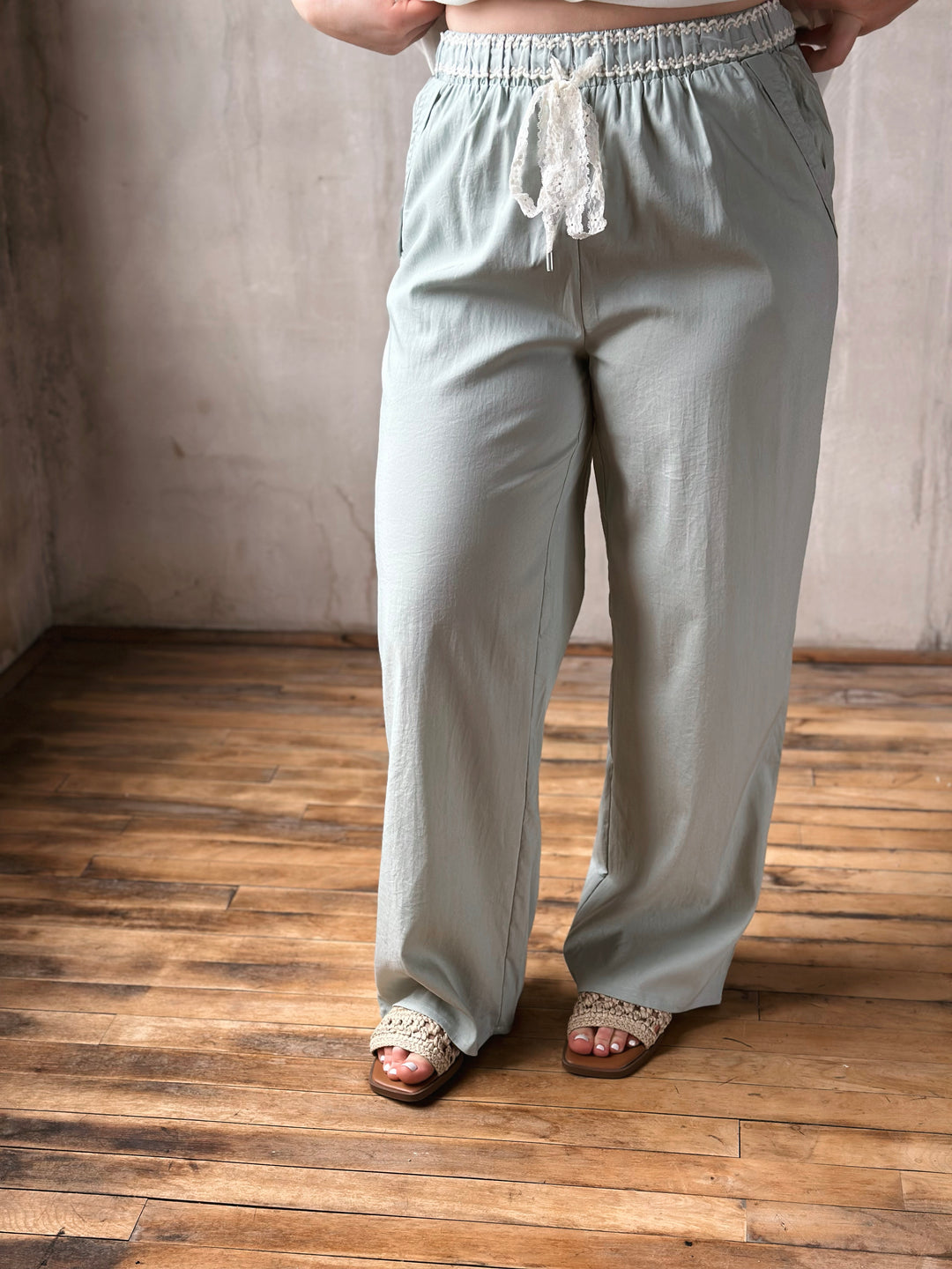 Light green pants worn by a person on a wooden floor with a neutral wall background