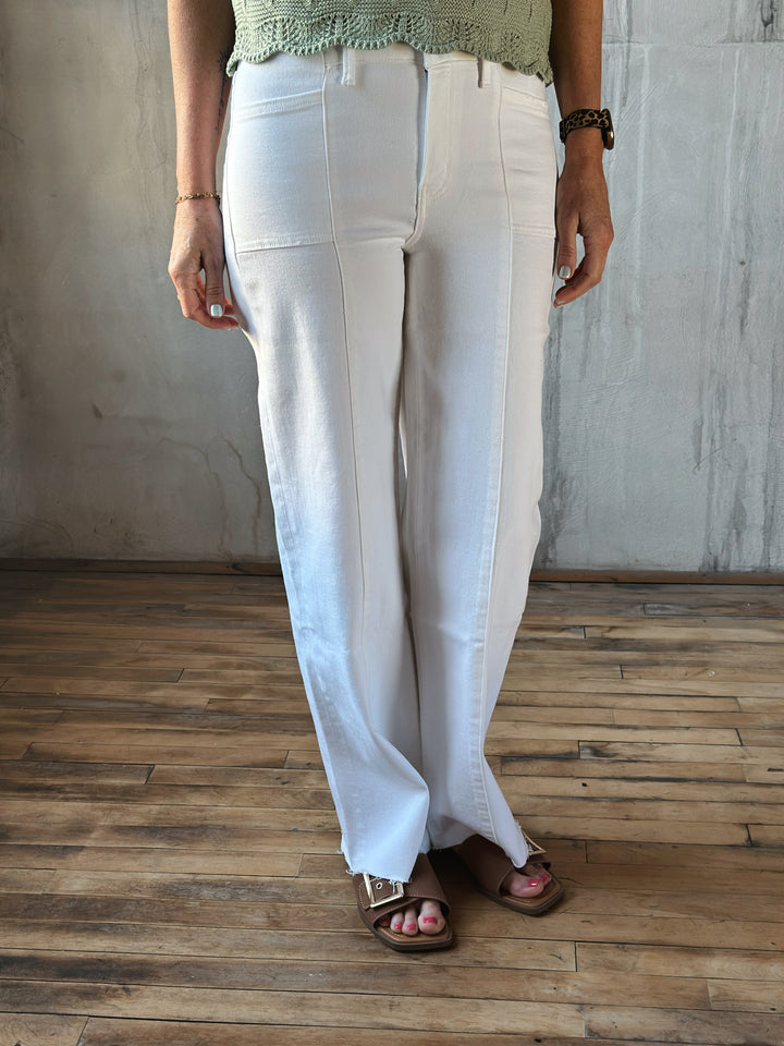 Person wearing white pants standing on a wooden floor with a neutral wall background