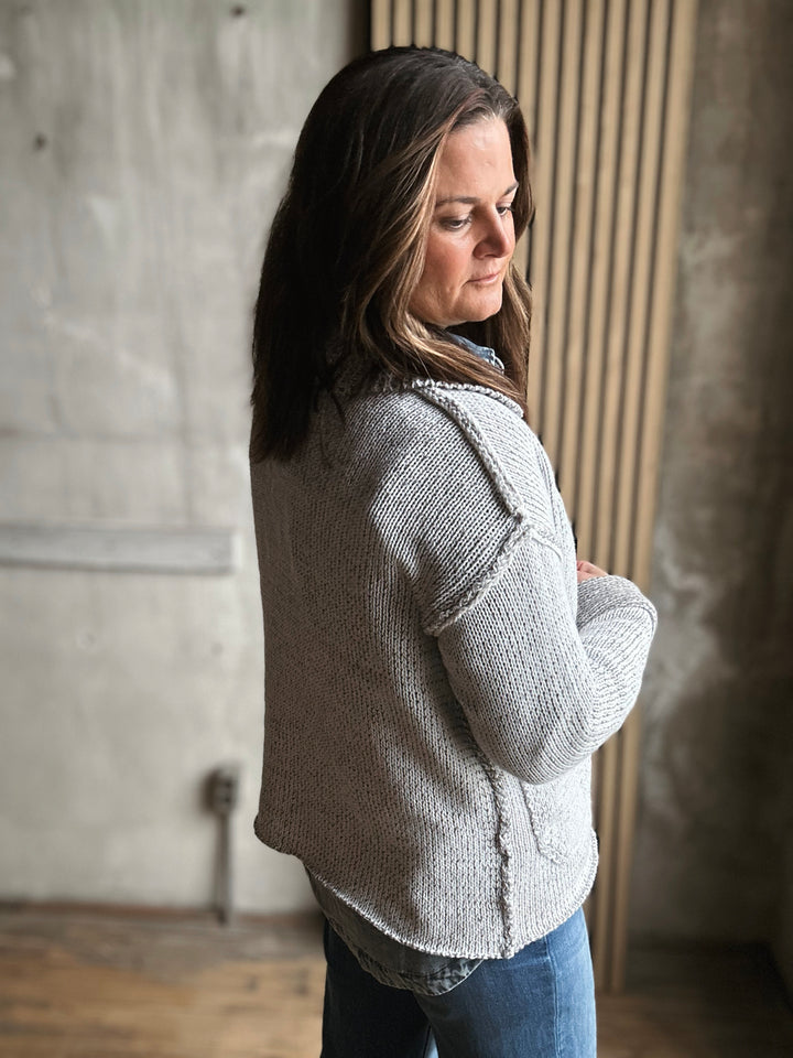 Woman wearing a gray knit cardigan in an indoor setting