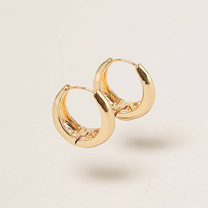 Gold hoop earrings on a light beige background
