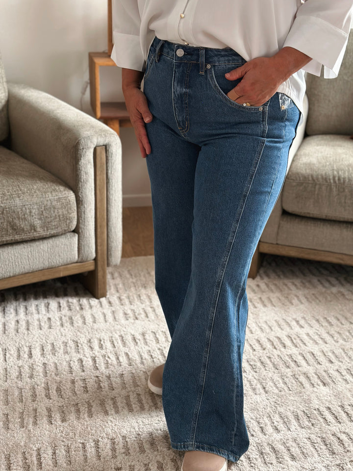 Person wearing blue jeans and a white shirt in a living room setting