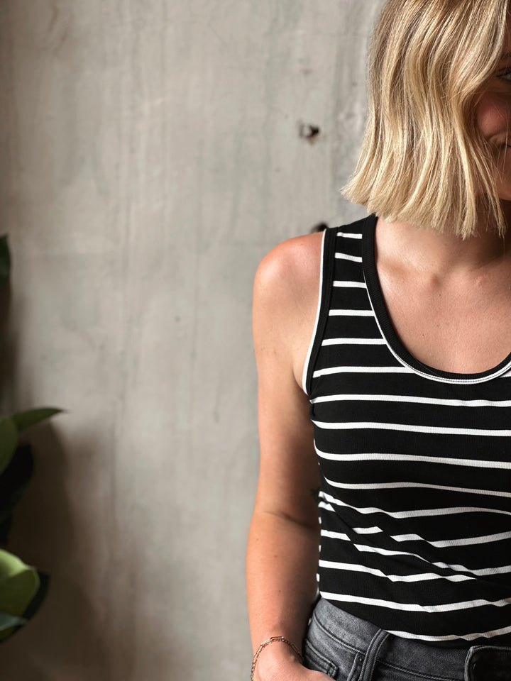 Person wearing a black and white striped tank top against a neutral background