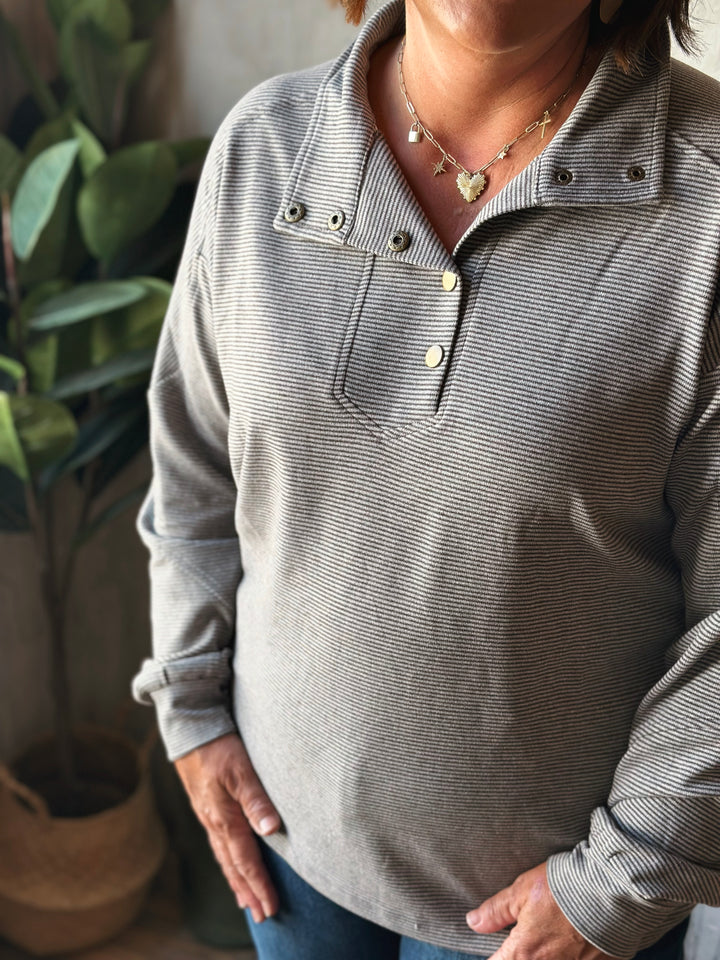 Person wearing a gray long-sleeve shirt with a blurred background