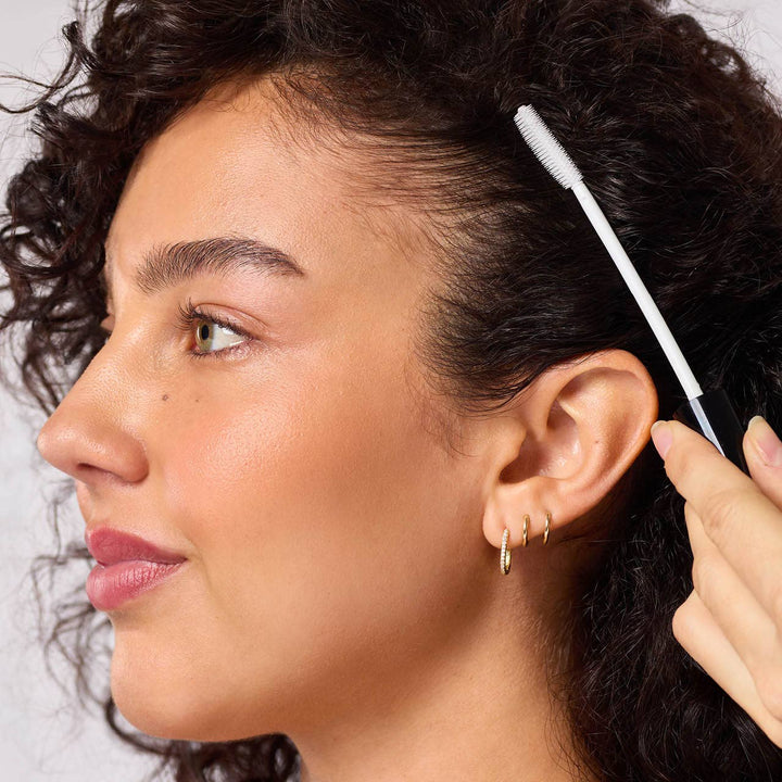 Close-up of a woman using an ear cleaning tool on her ear.
