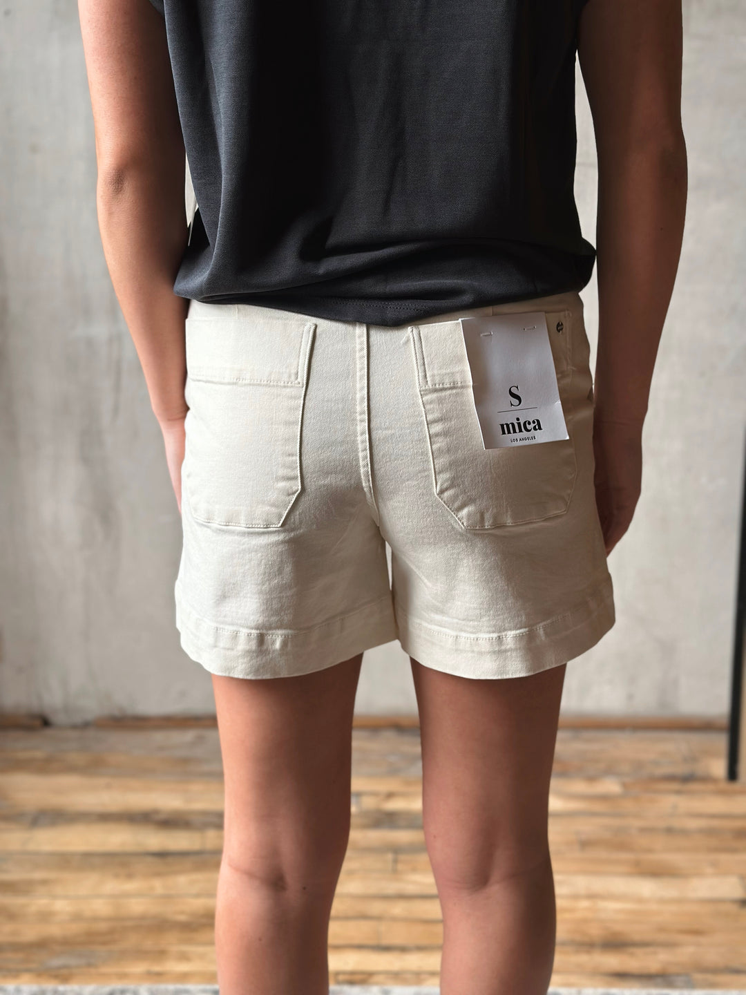 Person wearing beige shorts with a visible brand label against a neutral background