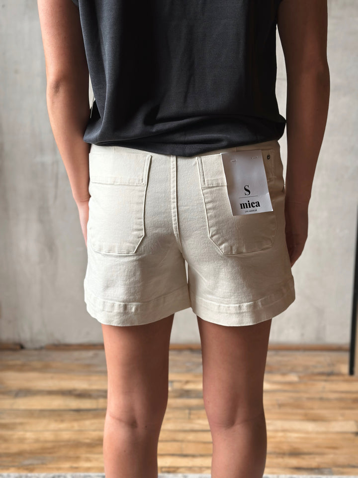Person wearing beige shorts with a visible brand label against a neutral background