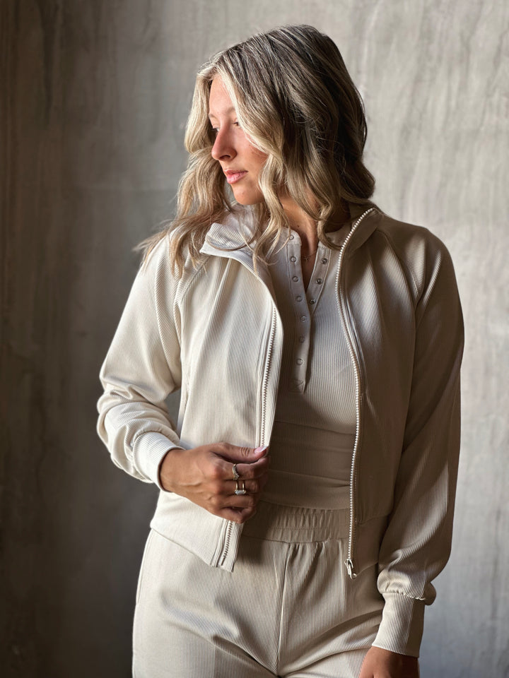 Woman wearing a beige tracksuit against a neutral background