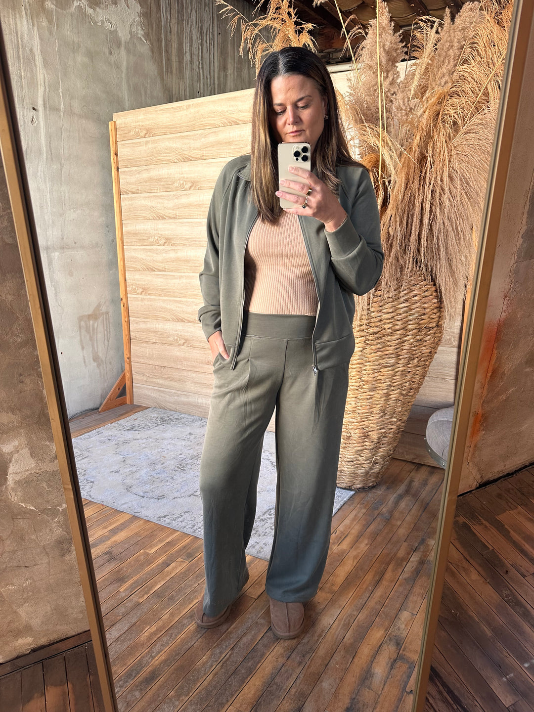 Olive green wide-leg pants styled with a matching zip jacket, mirror view