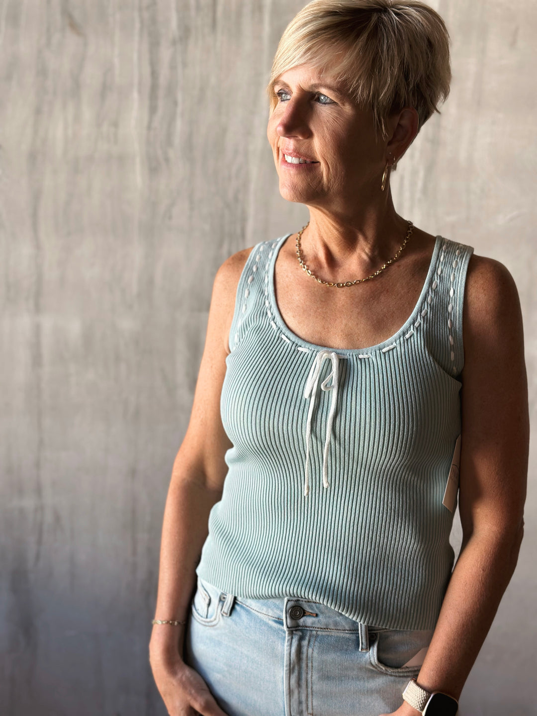 front view of sleeveless sweater knit tank features a flattering scoop neckline and a playful front tie detail. Mint top with white bow. 