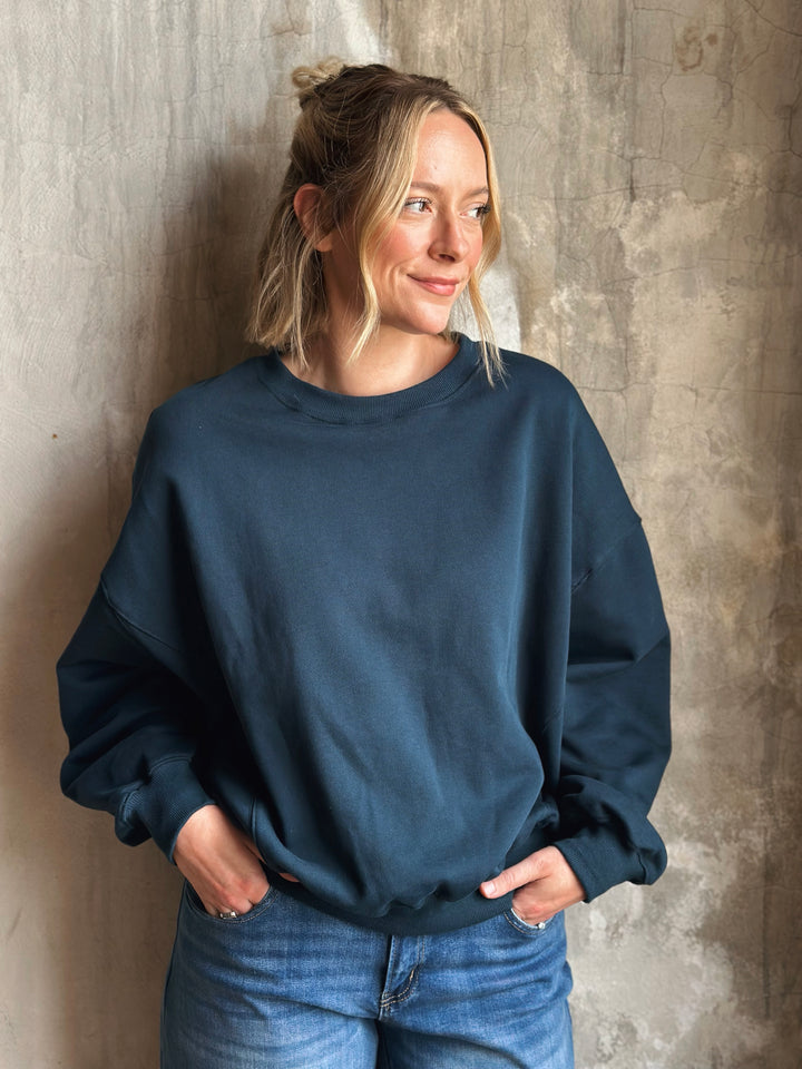 Person wearing a navy blue sweatshirt against a textured wall