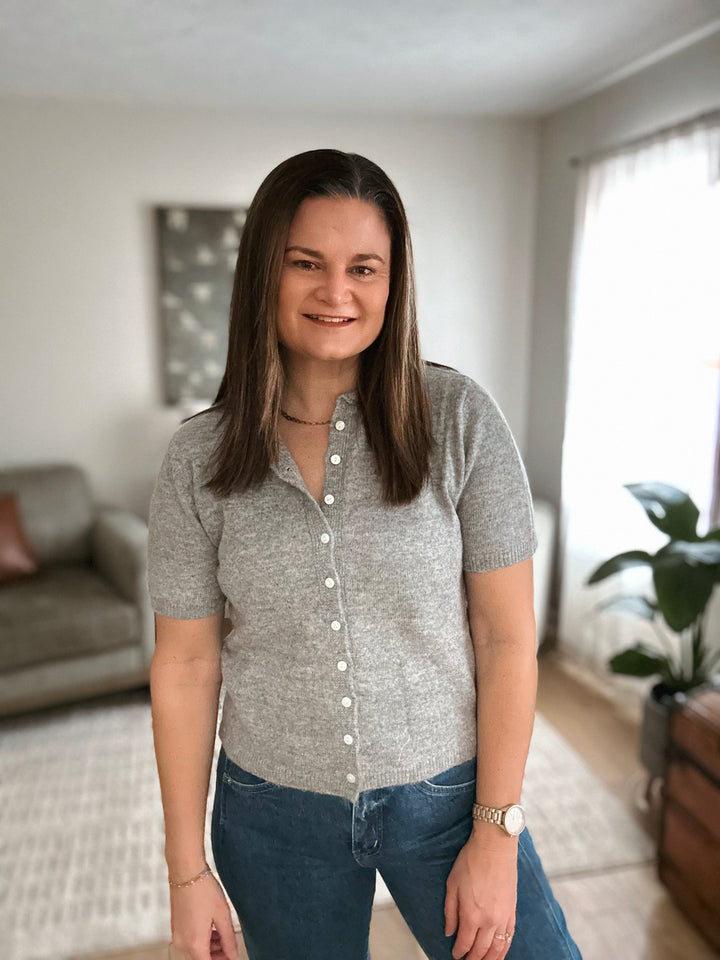 Woman wearing a gray short-sleeve cardigan in a living room setting