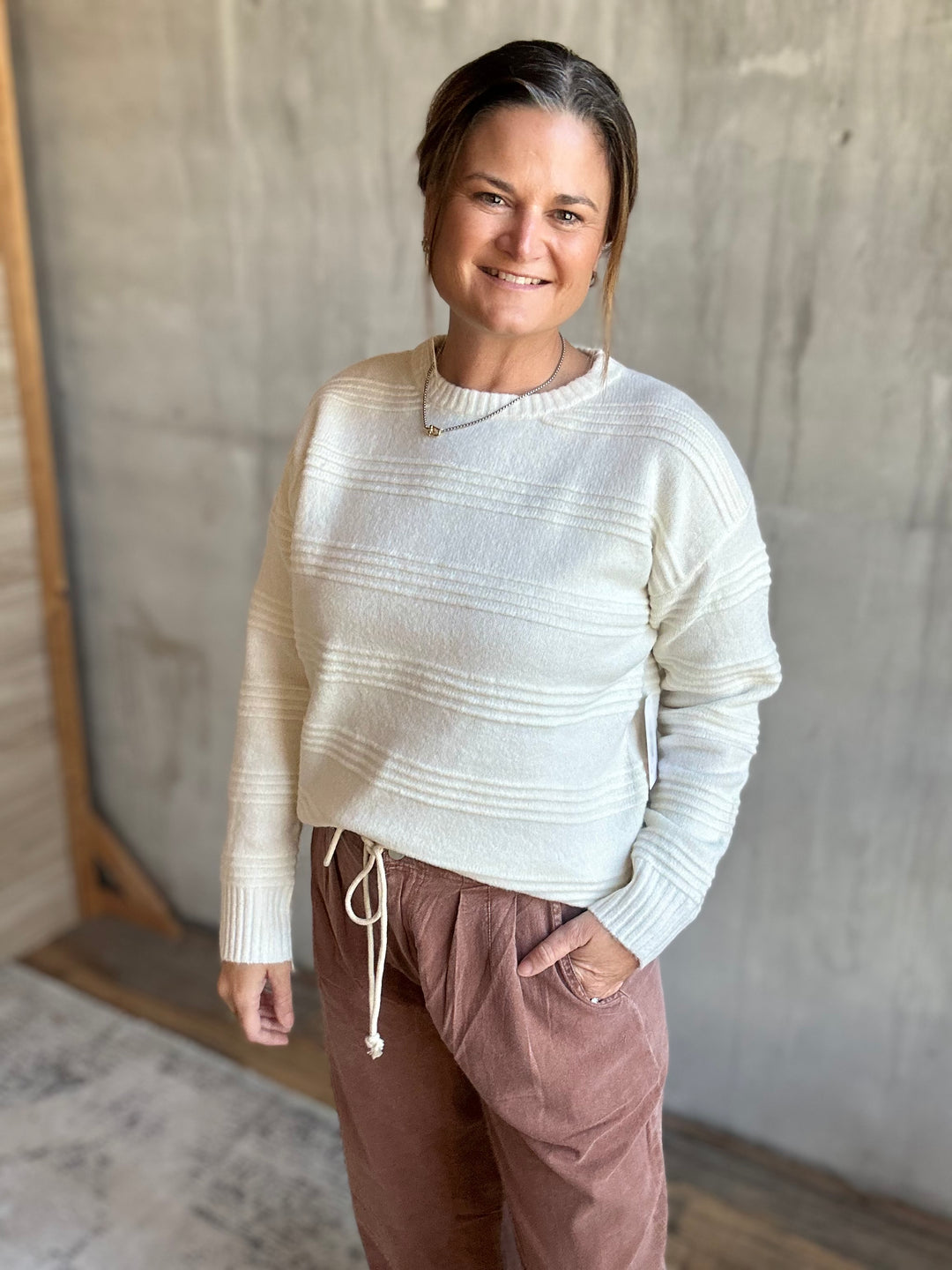 Woman in a cream crewneck sweater with a relaxed fit, angled view