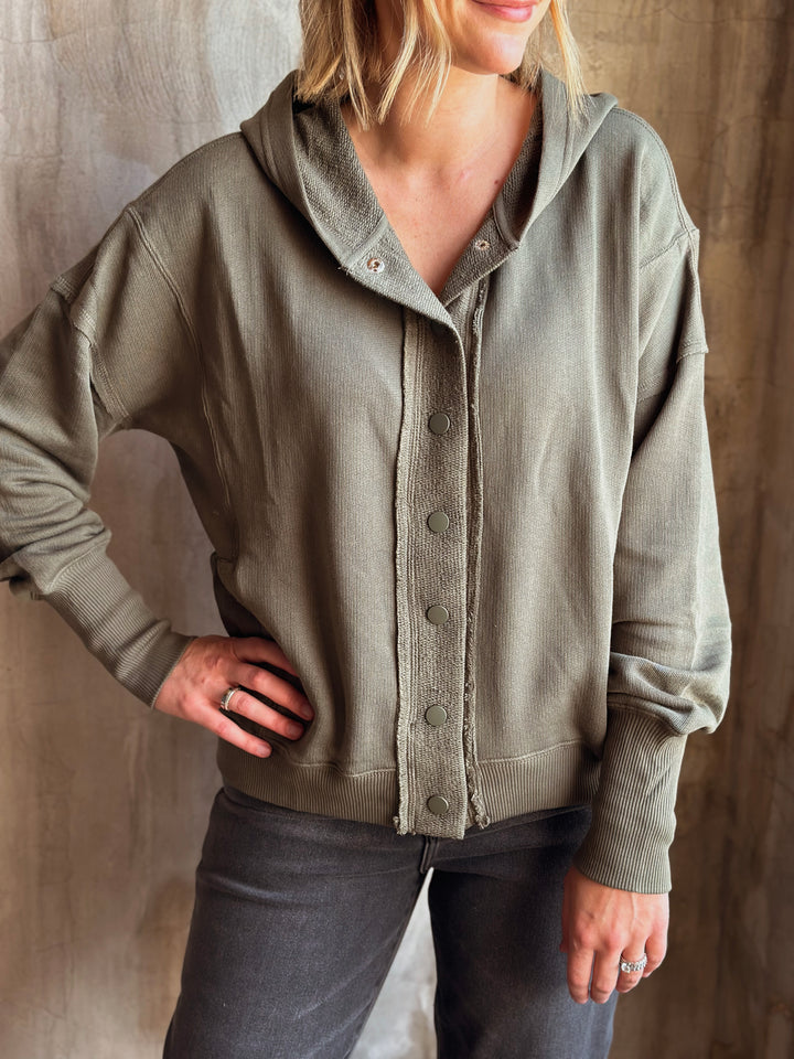 Person wearing a green cardigan against a neutral background