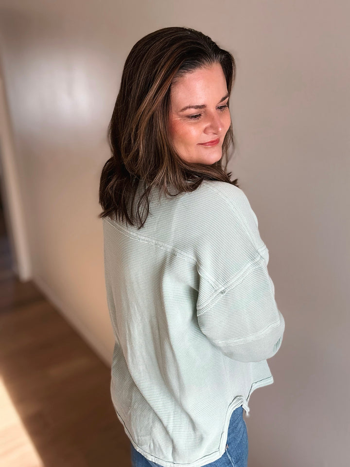 Woman wearing a light green sweater indoors with a neutral background