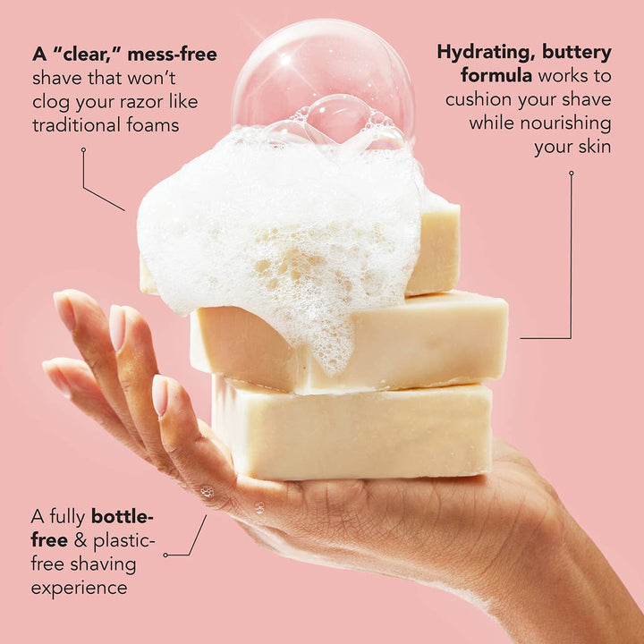 Three bars of soap with foam on a hand against a pink background, promoting a shaving product.