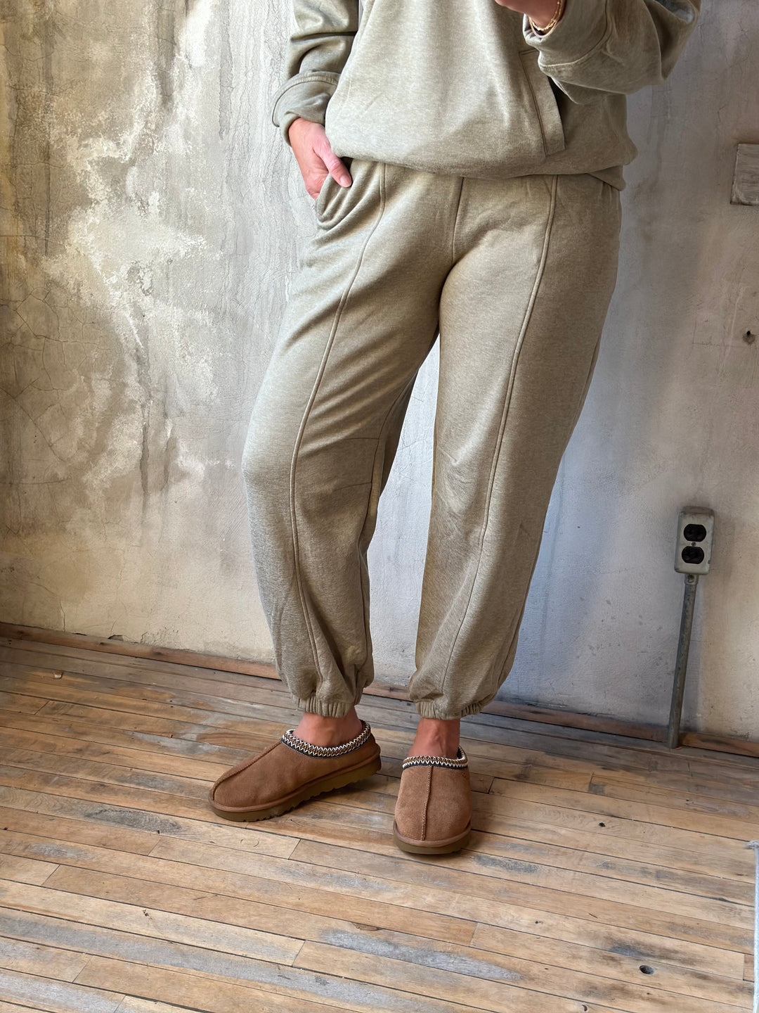 Khaki jogger pants with front seams and cuffed ankles, worn with a matching top